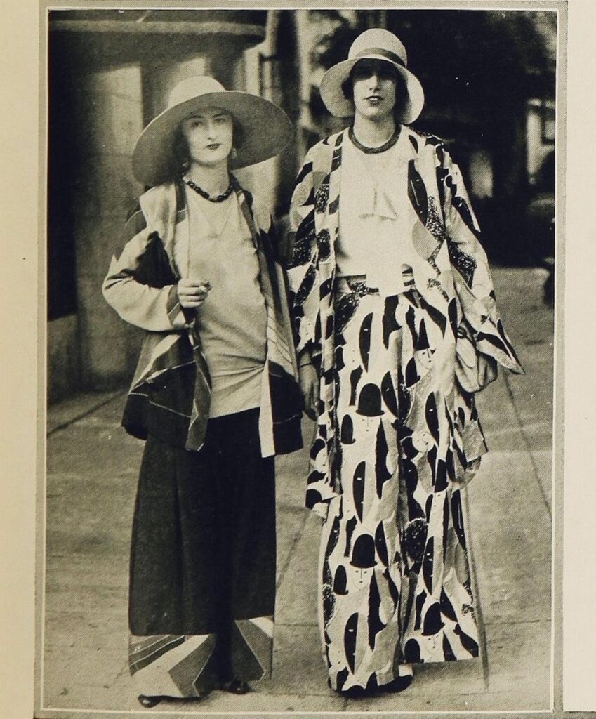 Two women standing in 1920s patterned beach pajamas and wide-brimmed hats.