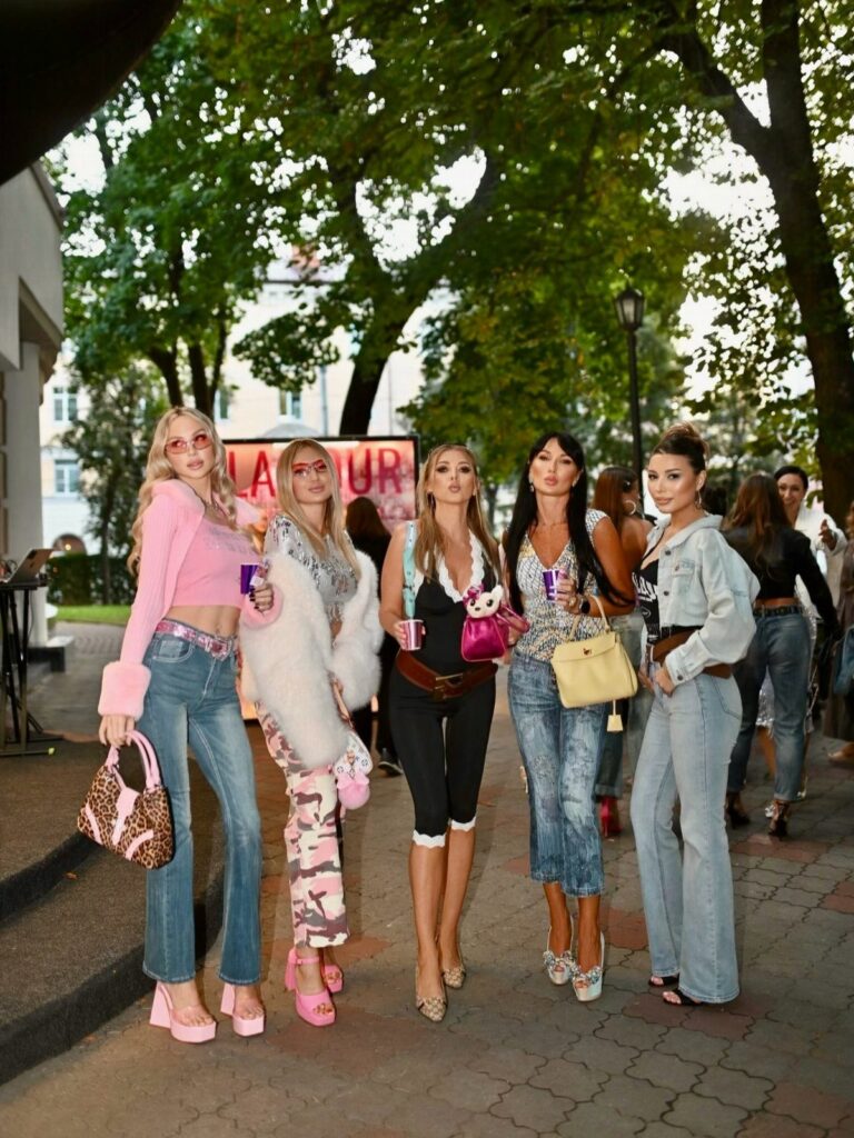 Five women posing outdoors wearing various colorful 2000s inspired fashion outfits and accessories.