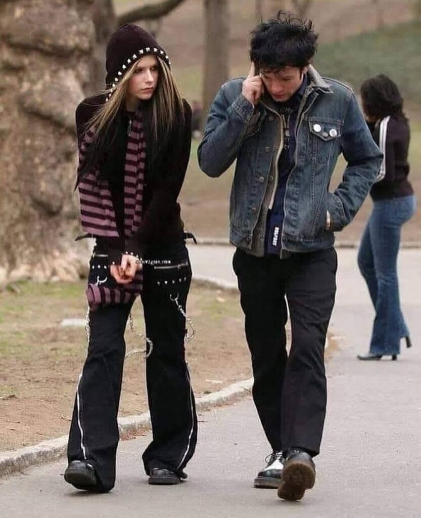 Woman in studded beanie and striped scarf walking alongside a man in a denim jacket.