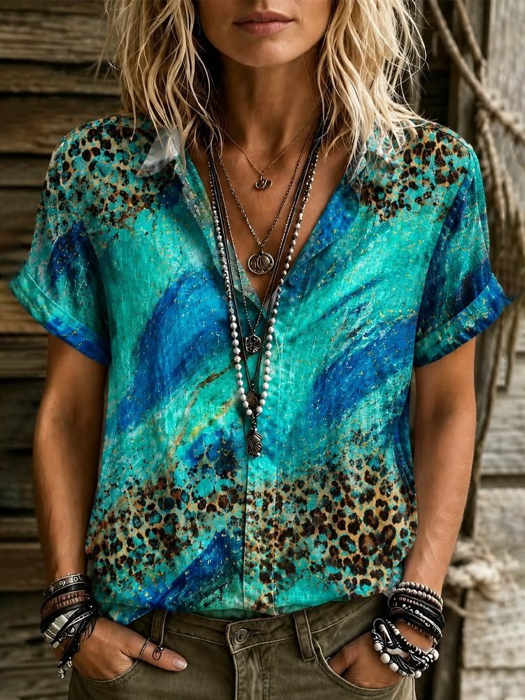 A person wearing a teal tie-dye shirt with leopard print patterns and layered necklaces.