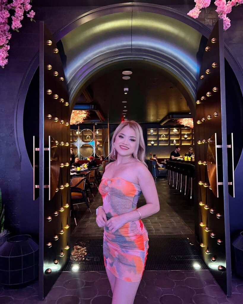 Blonde woman in a colorful strapless mini dress standing in a club entrance.